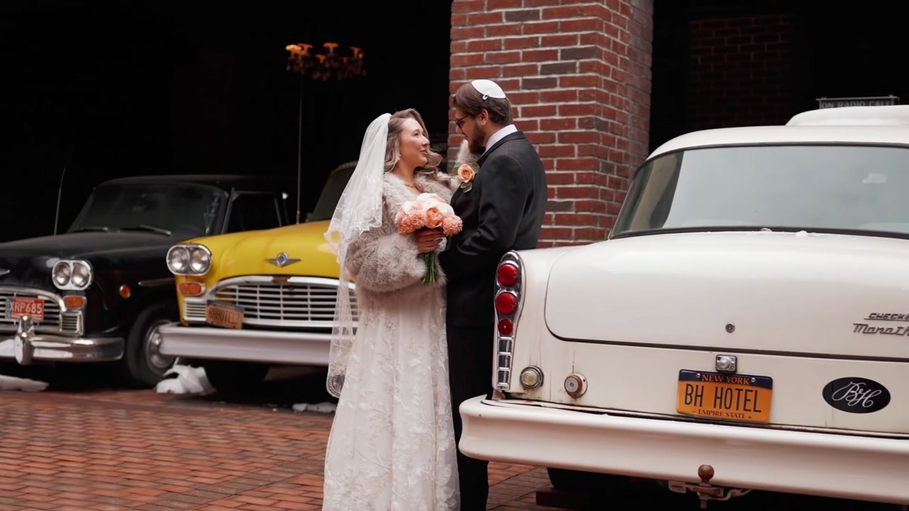 A newly married couple sharing a moment beside a vintage car